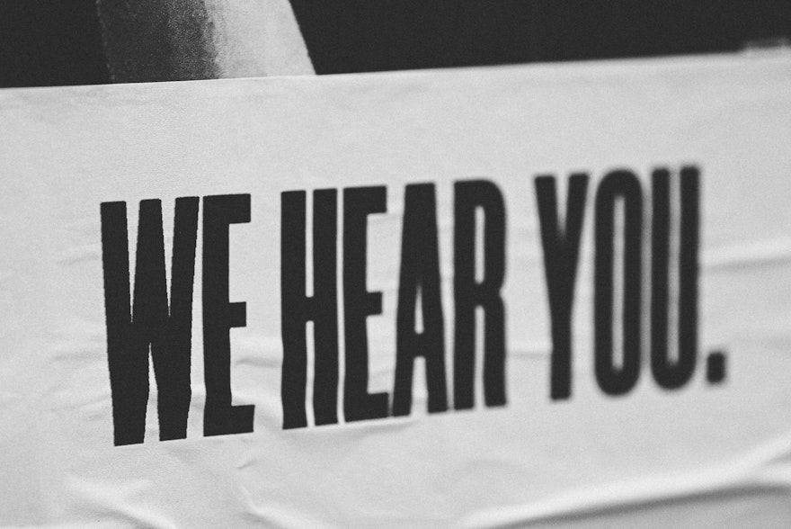 Banner with text we hear you in black capitals