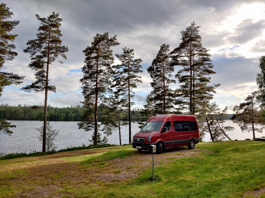 Ein roter Campervan steht ganz einsam auf einem offiziellen Campingplatz in Schweden