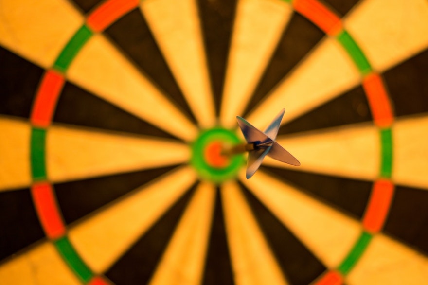 Dart board with dart in bullseye — Business goal setting obstacles
