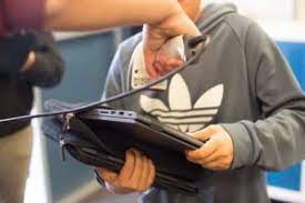 Student holds chromebook, while staff member scans it to check it in.