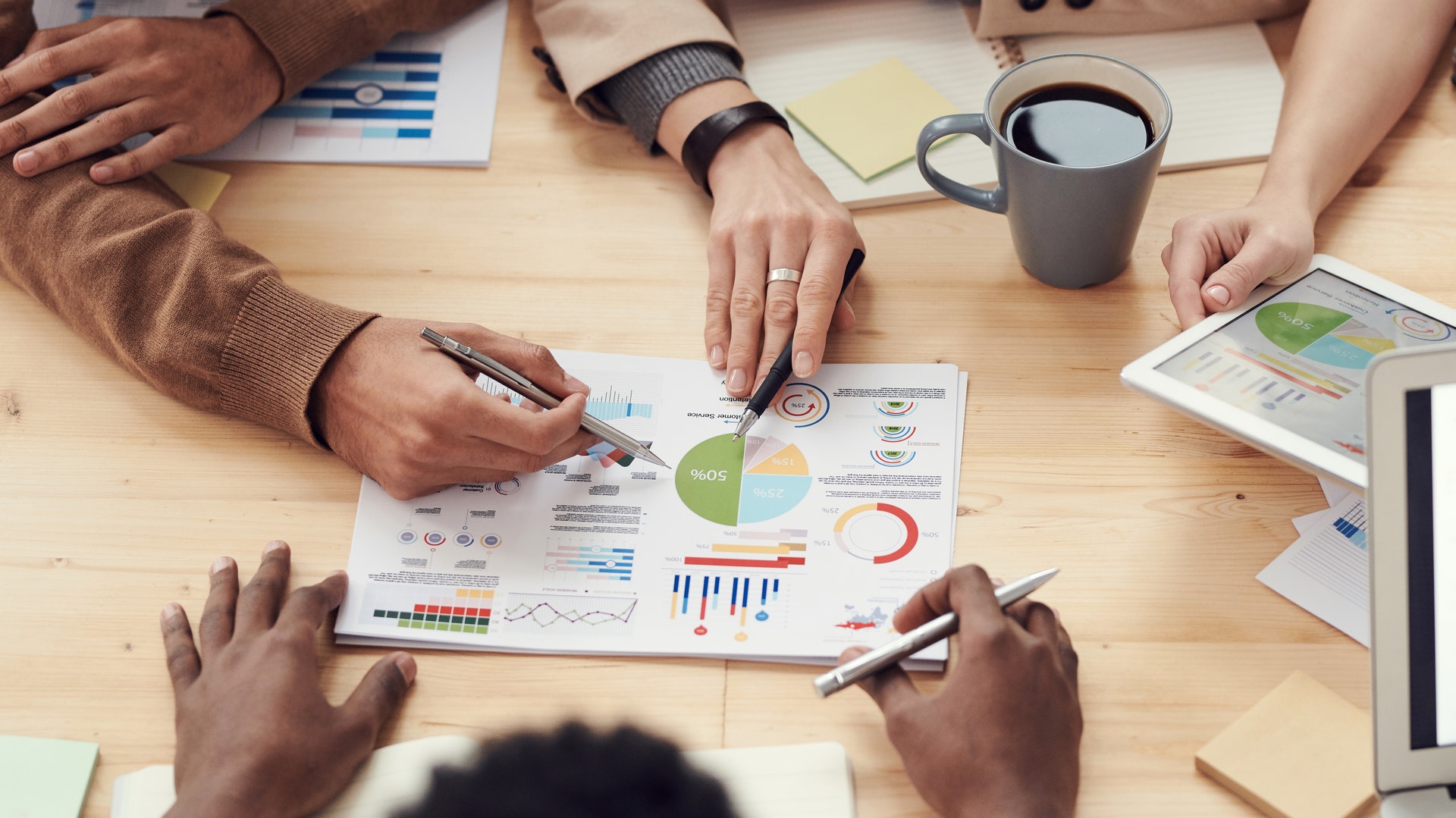 people gathered around a table explaining analytics written on paper