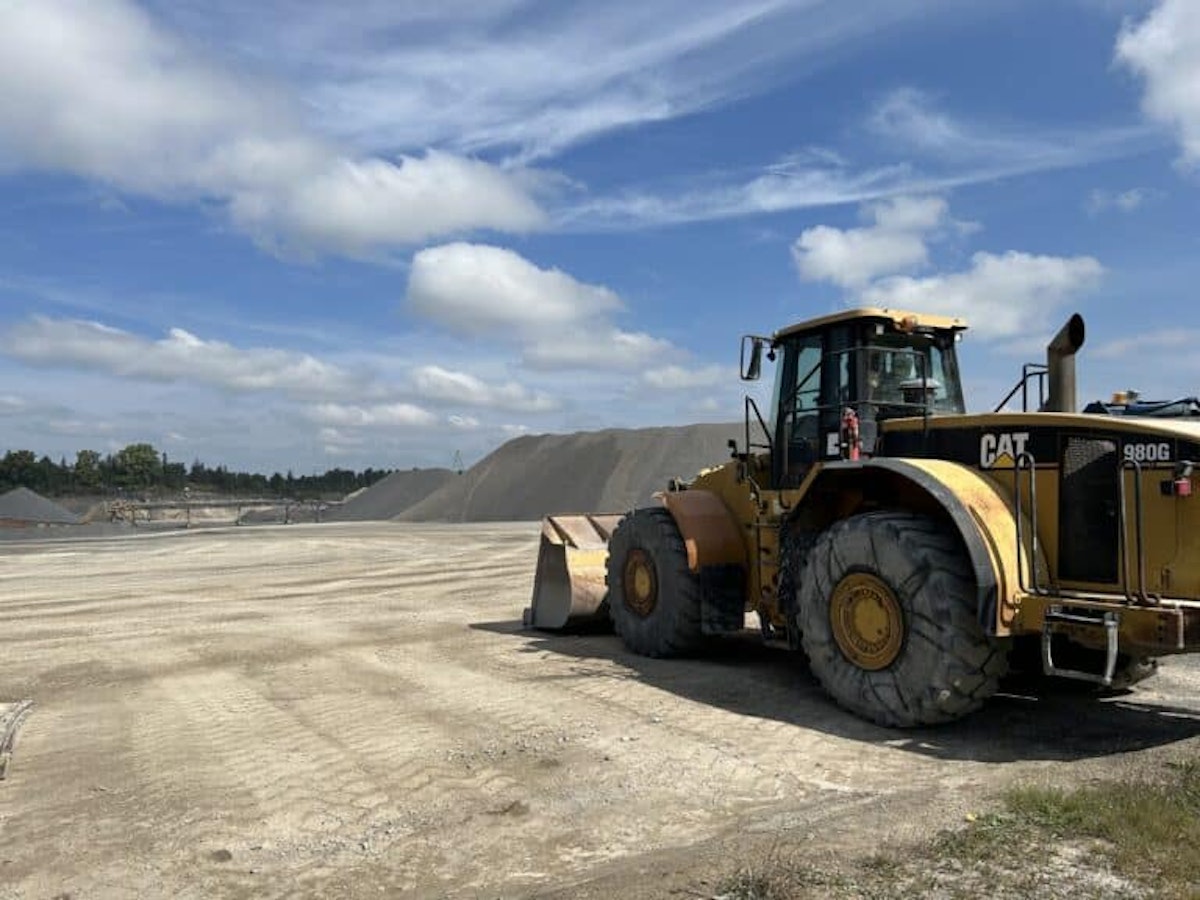 A large wheel loader sits on a prepared aggregate surface under a blue sky at an active construction or quarry site. The image symbolizes modern construction operations, efficiency, and the day-to-day environment where digital tools like Crewscope support crews and site leaders.