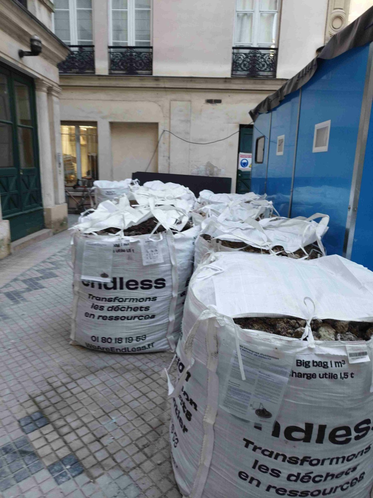 Chantier urbain propre et organisé avec des Big Bags EndLess fermés et alignés devant une façade en rénovation.