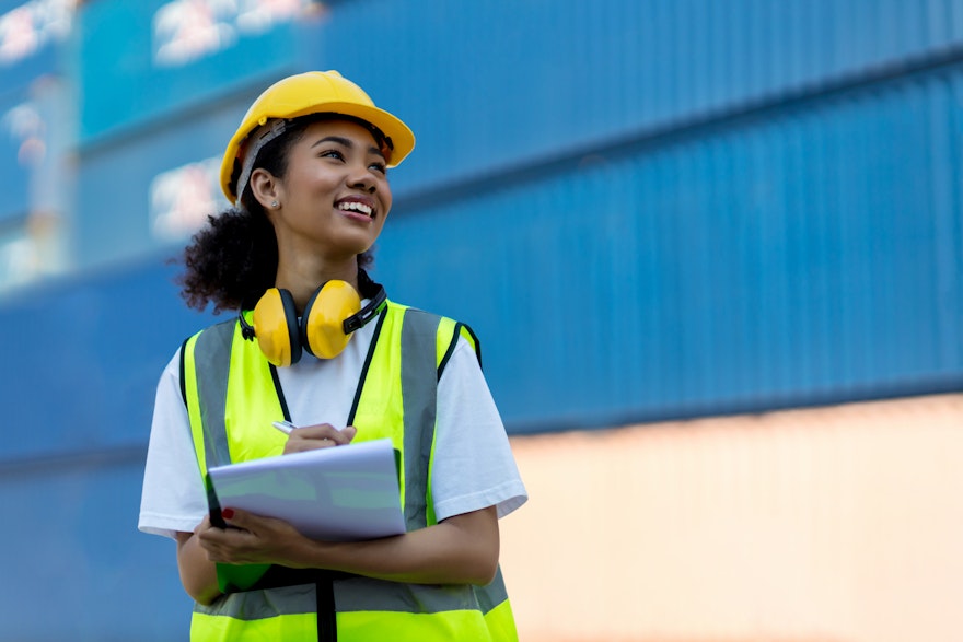 woman in hard hat holding tablet and smiling
